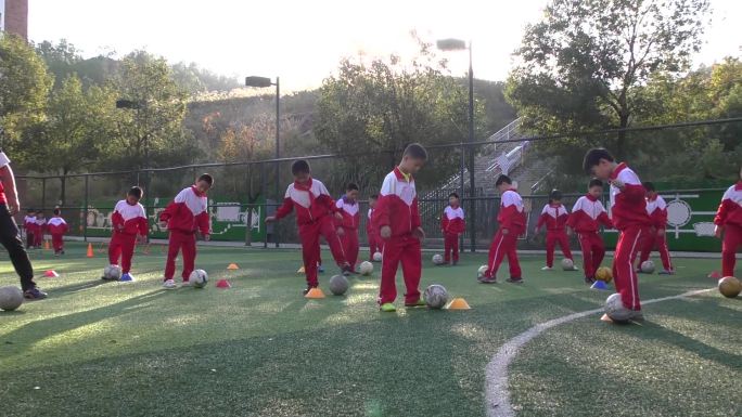 小学生在学校操场上练习踢足球的基本功