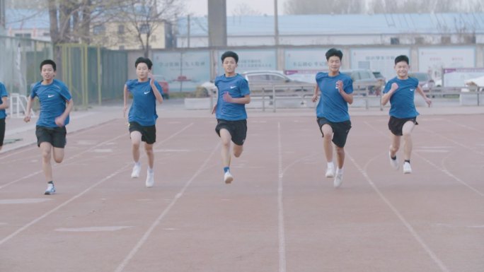 中学学生在校园里运动跑步踢足球