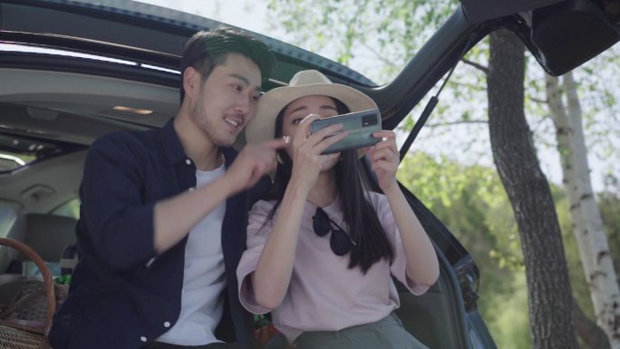 自驾游的青年夫妻用手机拍照