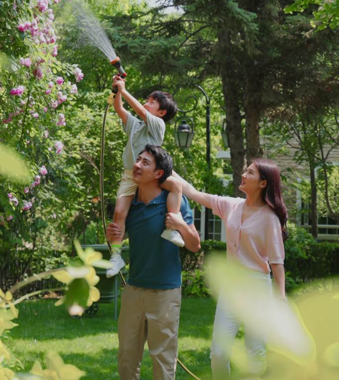 幸福的一家三口在院子里浇水