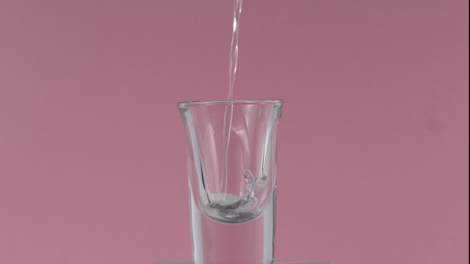 粉色背景白酒杯倒酒水实拍素材