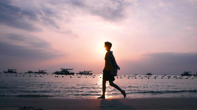 男孩在夕阳下的海边漫步沙滩