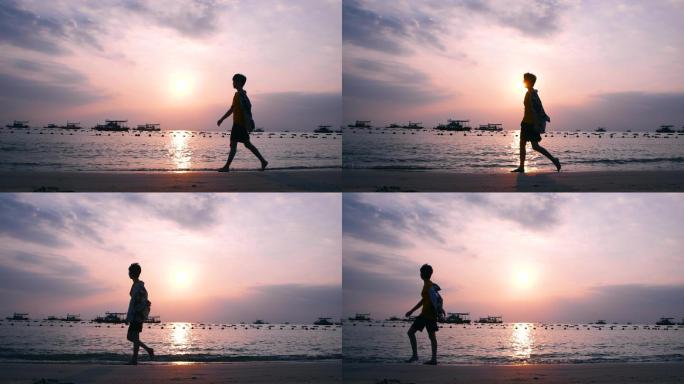 男孩在夕阳下的海边漫步沙滩