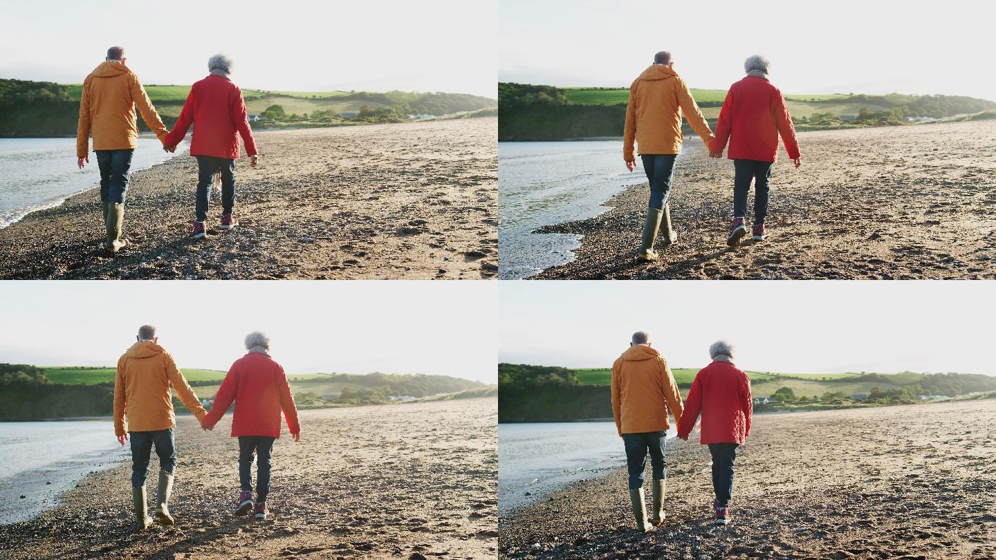 一对老年夫妇手牵着手沿着海岸线散步