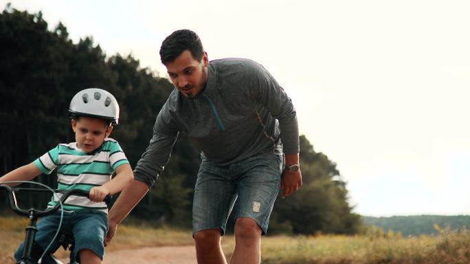 男人正在教他的小儿子骑自行车