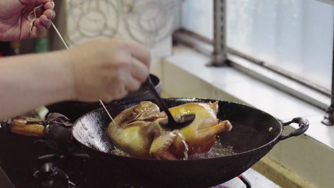 一位厨师在制作家庭炸鸡，炸制整鸡，油淋鸡