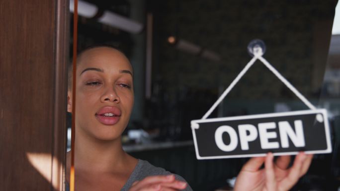 初创咖啡店或餐厅的女店主打开门上的标志