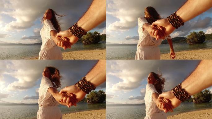 一个快乐的年轻女子牵着男友的手在海滩上