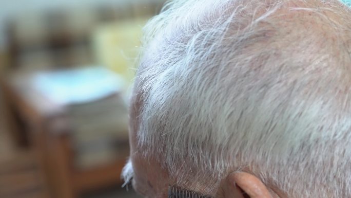 理发师正在给一位头发斑白的老人剪头发