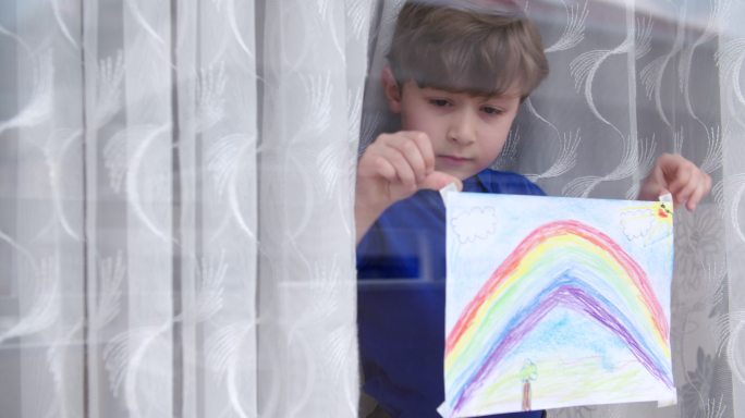 一名男孩画着彩虹贴在玻璃上