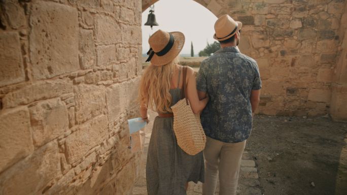 年轻游客夫妇参观地中海岛上的老石教堂