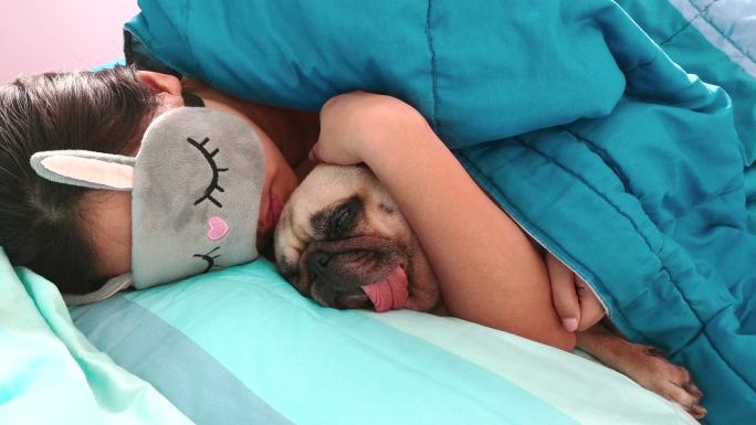 戴着眼罩的女子躺在床上抱着狗睡觉