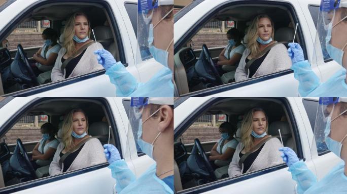 护士在室外拿着棉签和坐在车里的妇女谈论检