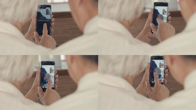 爷爷奶奶在家里用智能手机和孙子交谈