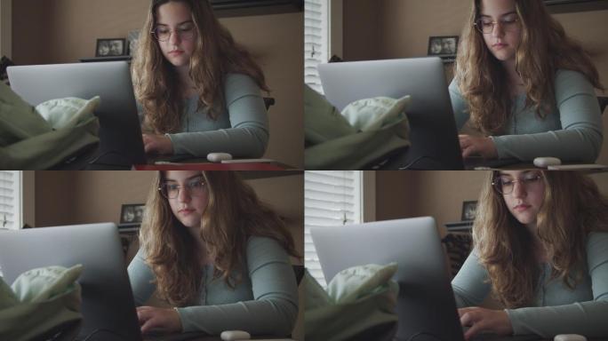 一个十几岁的女孩在家用笔记本电脑做功课