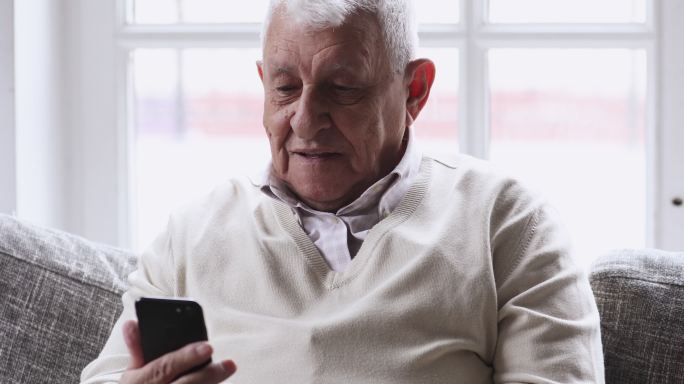 快乐老人使用智能手机在沙发上