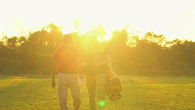 高尔夫手与球童交谈高尔夫球袋日落