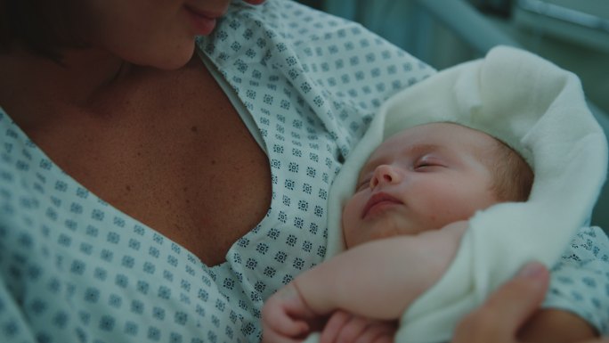 母亲在医院里看着熟睡的新生儿