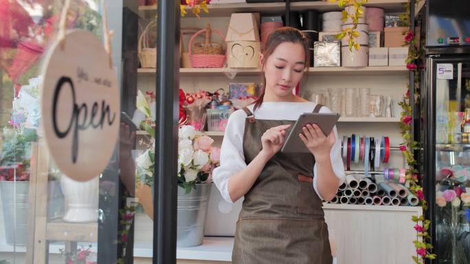 店长站在店里使用平板电脑工作