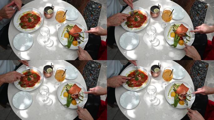 在餐桌上吃饭的男人和女人的手