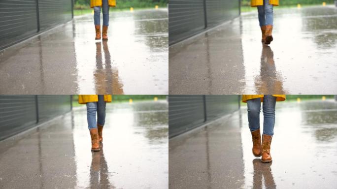 穿着黄色防水靴的脚在雨中走向摄像机。
