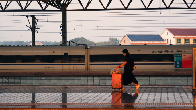 高铁站进站的列车和推着行李箱的旅客行人
