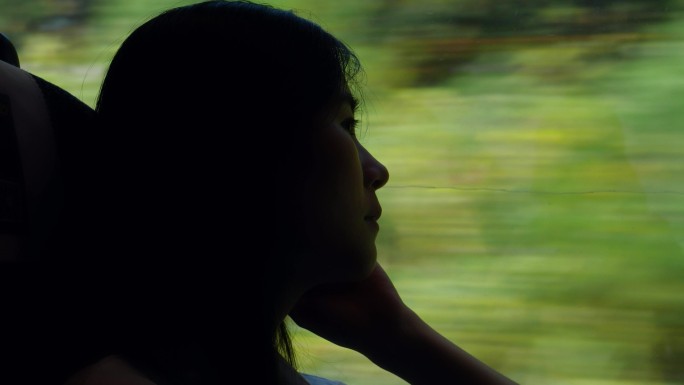 女孩坐火车看向窗外思考的剪影