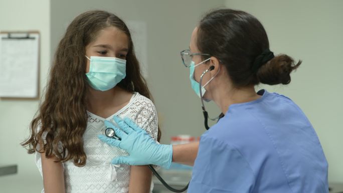 12岁女孩在医生检查时戴着防护面罩