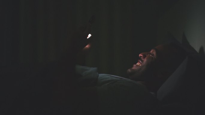 躺在床上玩手机的男人