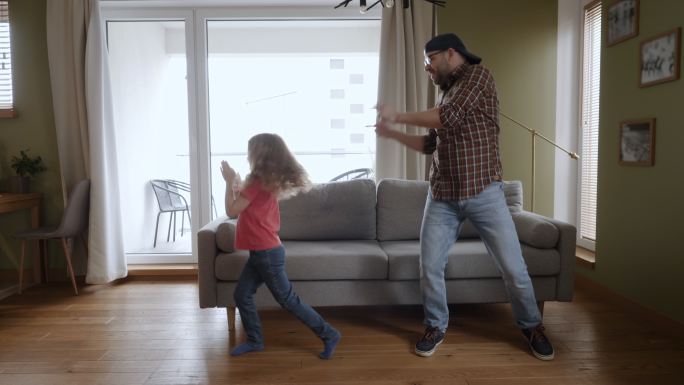 快乐的父亲和女儿在家客厅跳舞