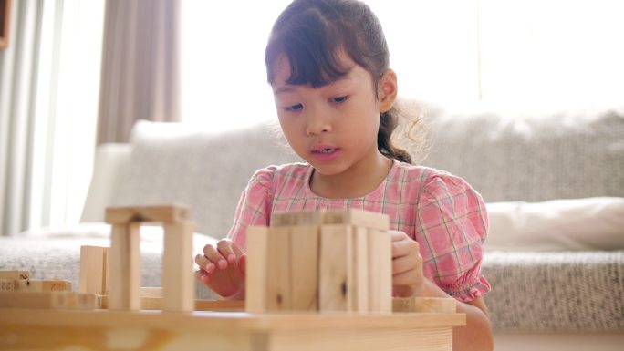 小女孩在家里的起居室里搭建木块