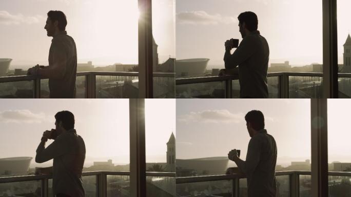 一名男子站在公寓阳台上喝咖啡