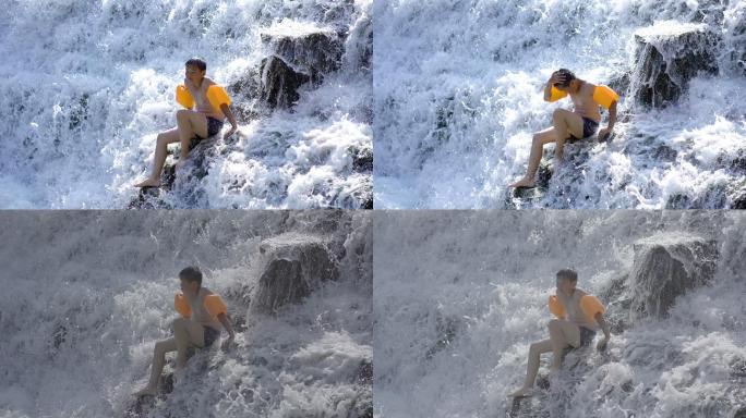 小男孩坐在流水的石阶上