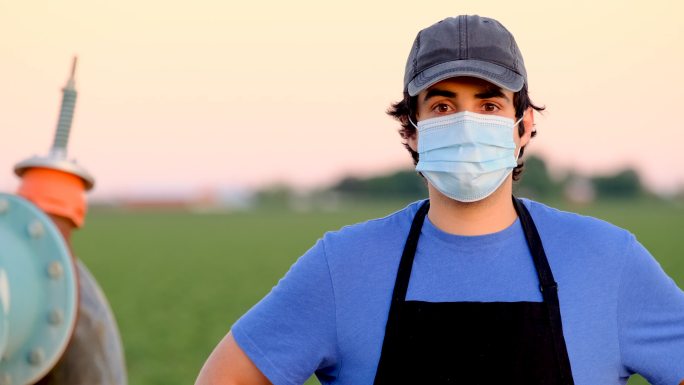 年轻的农场工人戴着口罩看着镜头