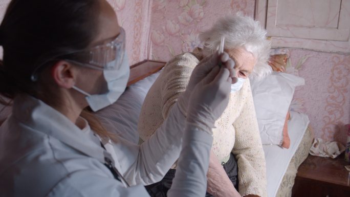 女医生在家里给一位老年妇女接种疫苗。