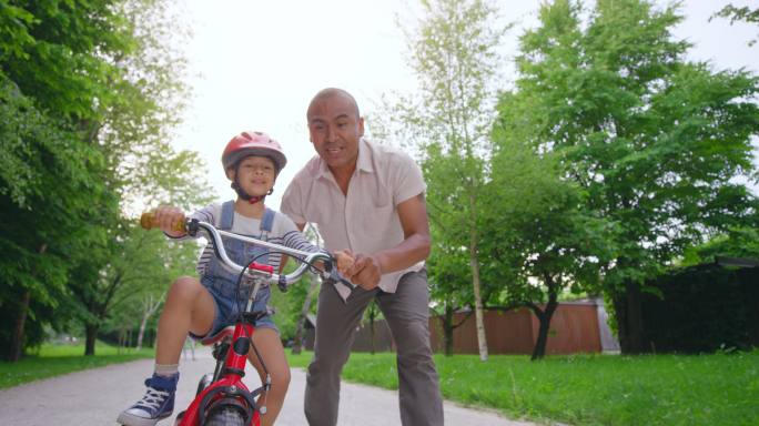 儿子学骑自行车父子运动爸爸教儿子学骑自行