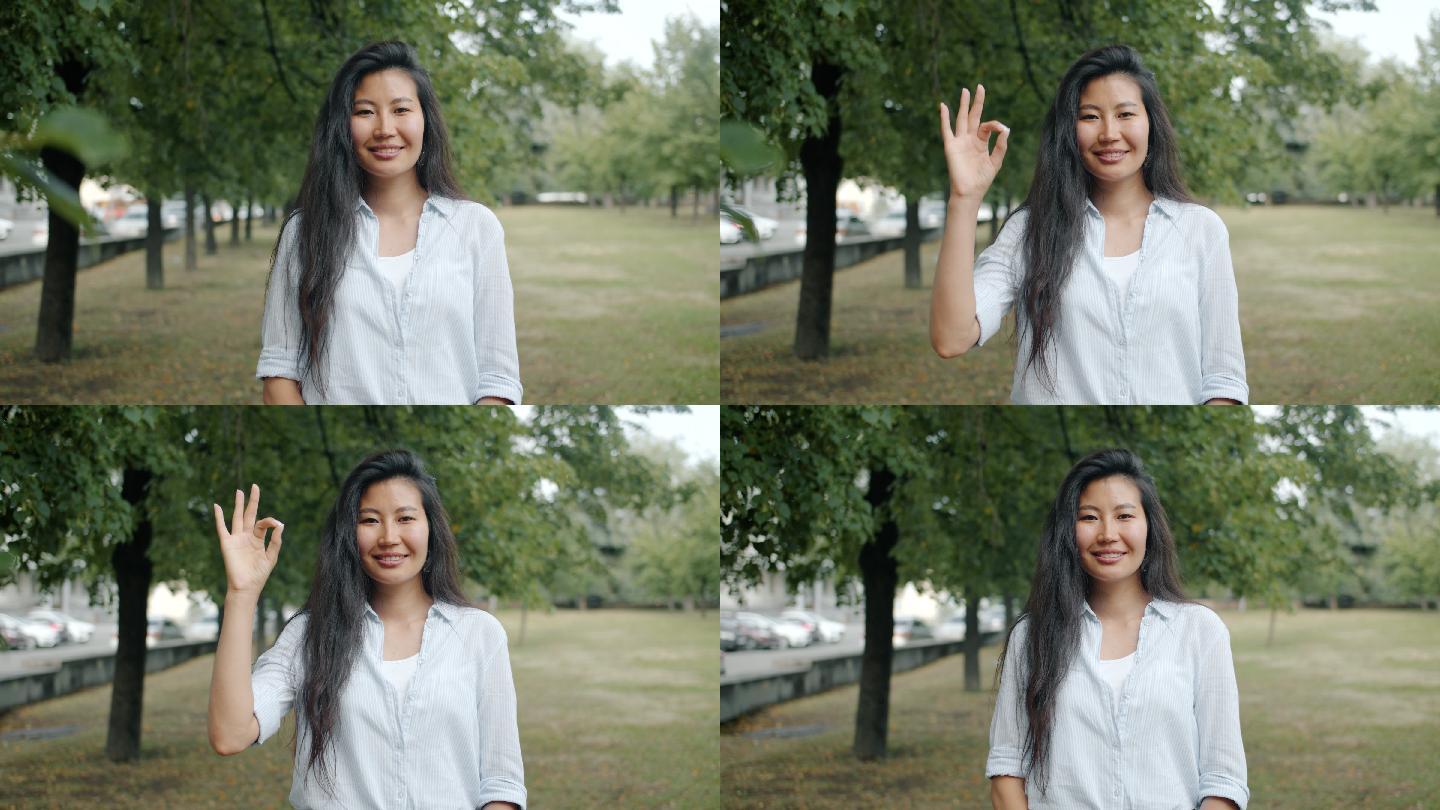 美丽的亚洲女人在城市公园展示OK手势