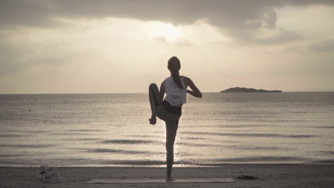 女性在海滩练习瑜伽的广角视频