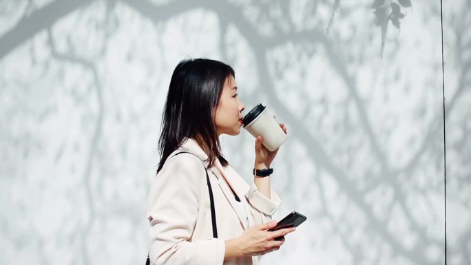 年轻女子一边在街上散步一边喝咖啡