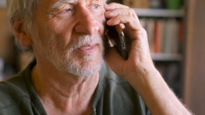 老人在家里用智能手机手机聊天