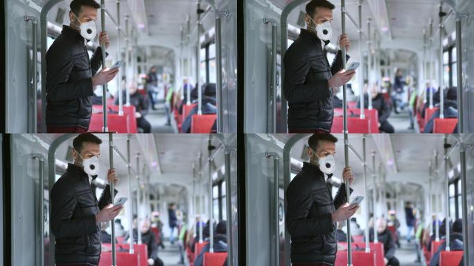 乘坐有轨电车的男子戴着防护面罩使用手机