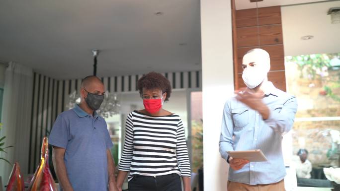 一对戴着口罩的夫妇参观一所出售的房子