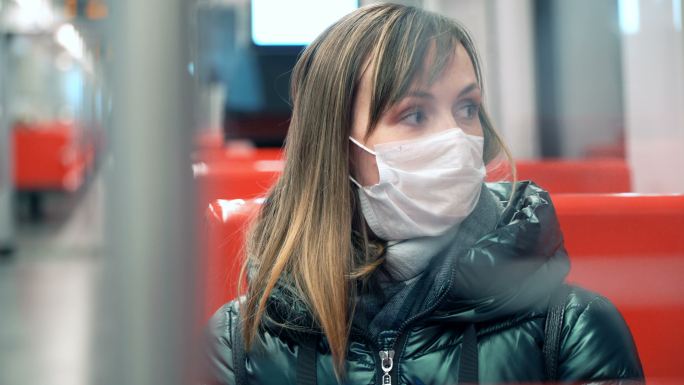 地铁车厢里戴着医用口罩的年轻女子