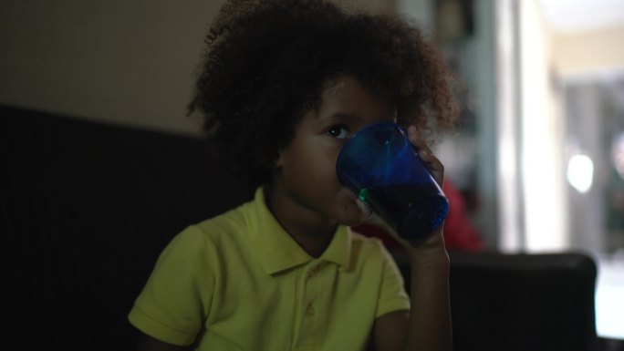 小男孩在客厅看电视喝着水