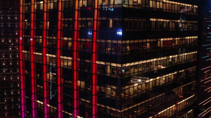 大城市夜晚办公楼的玻璃窗和内部加班情景