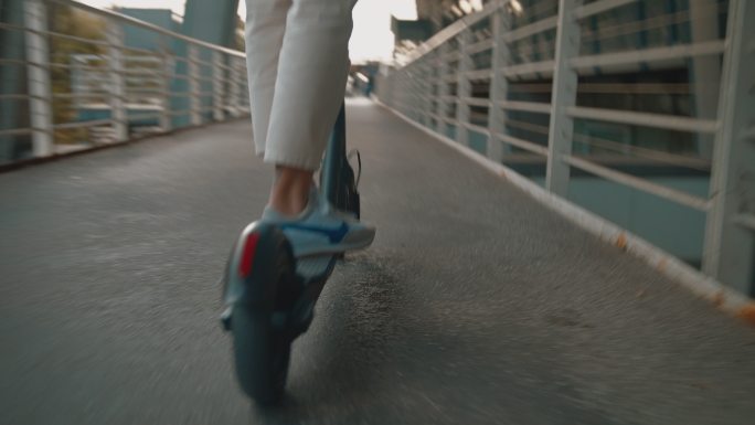 女性在行人天桥上骑电动推式踏板车