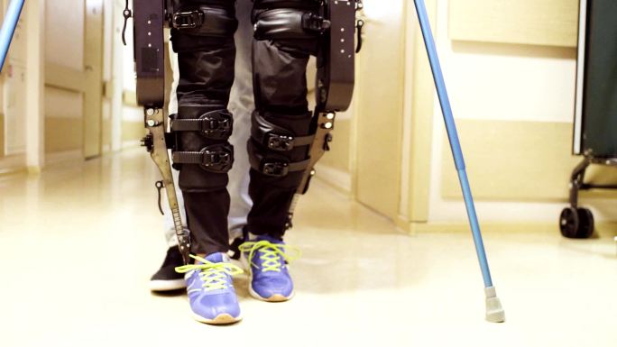 医生帮助用两根手杖支撑的矫形器行走的患者