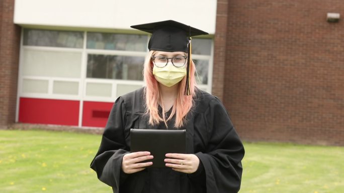 高中毕业生戴着口罩手持毕业证书