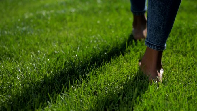 裸足少女在草地上行走的特写镜头
