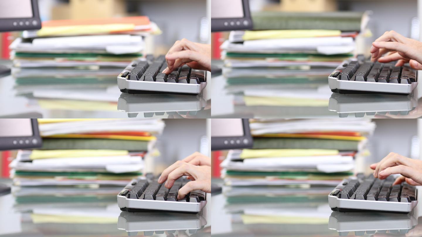 办公室职员在电脑键盘上打字，堆放文件